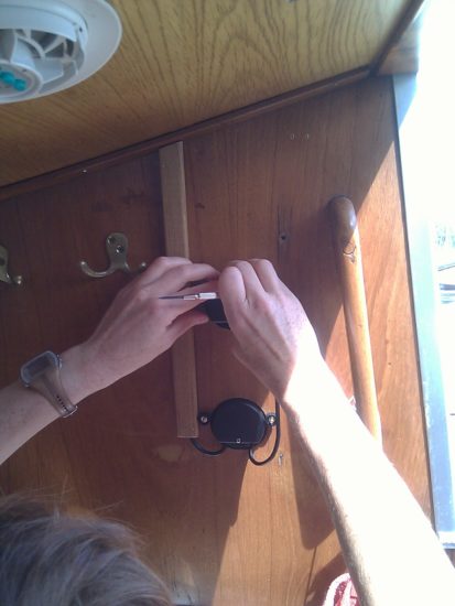 Julie spänner upp kabeln som går mellan instrumenten NX Wind (övre) och NX Sea Data (nedre). Tidigare gick 4 kablar här till logg och ekolod. Nu behövs bara en kabel från WSI-boxen till instrumenten som är kopplade i serie.